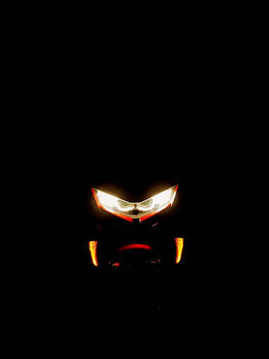 The scooter's front LED headlight and indicators glowing in the dark.